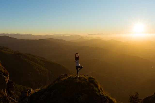 Personne faisant du yoga sur une colline